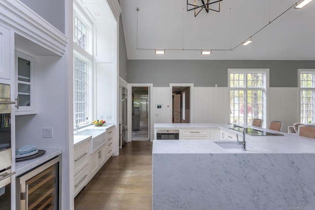 kitchen with beverage cooler, dark wood-style flooring, white cabinetry, and a sink