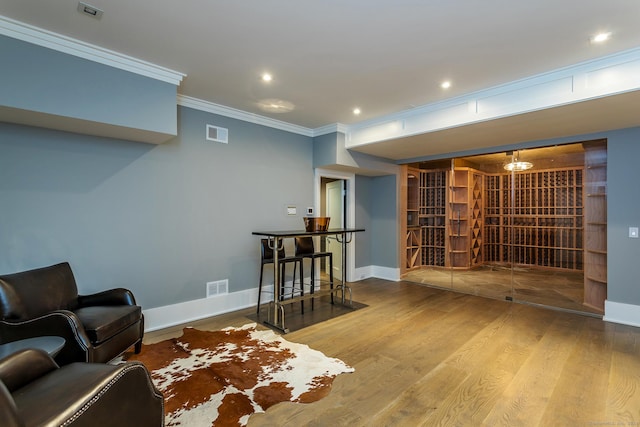 living area with visible vents, baseboards, wood finished floors, and ornamental molding