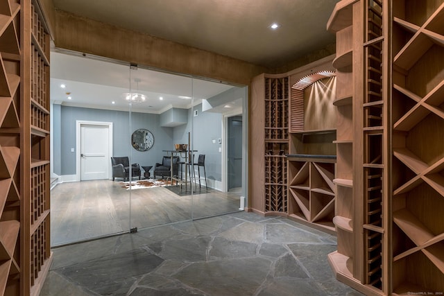 wine cellar featuring recessed lighting, baseboards, ornamental molding, and stone finish floor