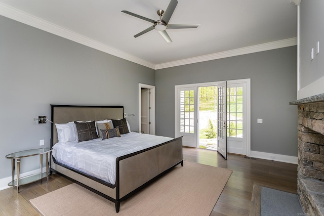 bedroom featuring a fireplace, wood finished floors, baseboards, and ornamental molding