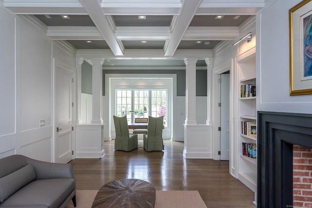 living area featuring coffered ceiling, ornate columns, a fireplace, beamed ceiling, and a decorative wall