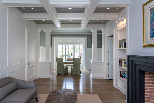 living area featuring a decorative wall, coffered ceiling, decorative columns, and beam ceiling