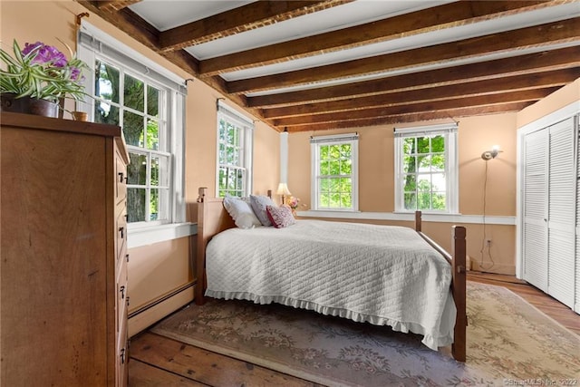 bedroom featuring dark hardwood / wood-style flooring, baseboard heating, and beamed ceiling