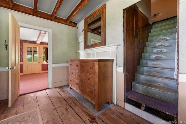 stairs featuring light carpet and beam ceiling