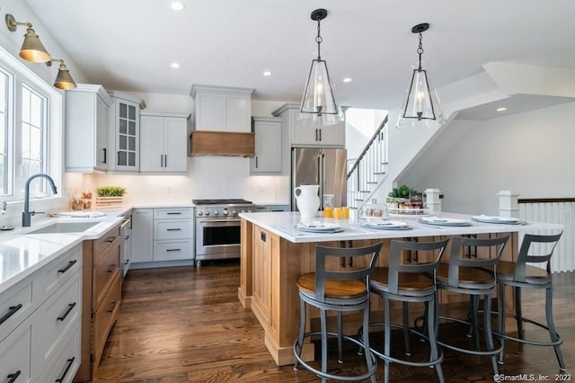 kitchen with premium appliances, a breakfast bar, a center island, tasteful backsplash, and dark hardwood / wood-style flooring