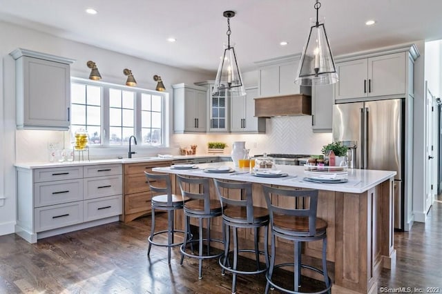 kitchen featuring a center island, backsplash, decorative light fixtures, dark hardwood / wood-style flooring, and a kitchen breakfast bar