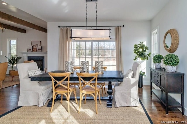 dining space with plenty of natural light, beam ceiling, and dark wood-type flooring