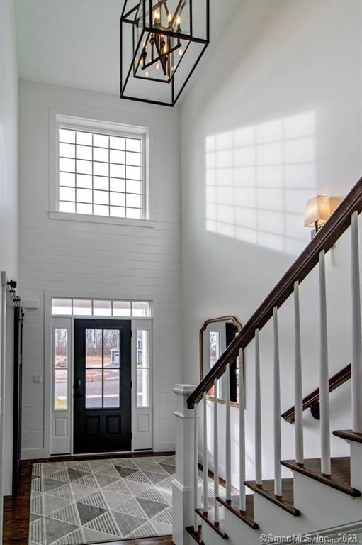 foyer with a notable chandelier, brick wall, dark wood-type flooring, and high vaulted ceiling