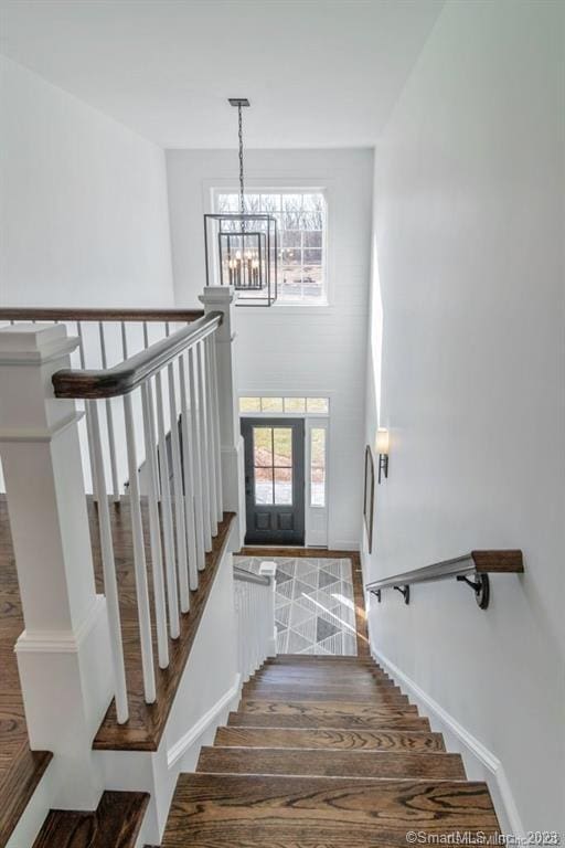 stairway featuring dark hardwood / wood-style flooring, an inviting chandelier, and a high ceiling