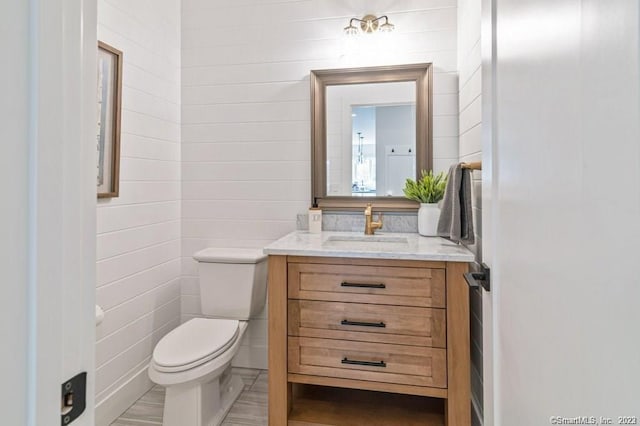 bathroom featuring tile walls, toilet, and vanity