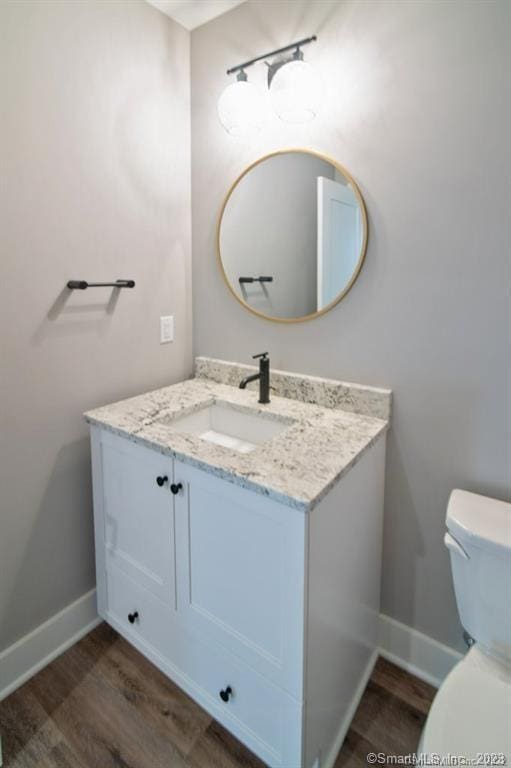 bathroom with toilet, wood-type flooring, and vanity