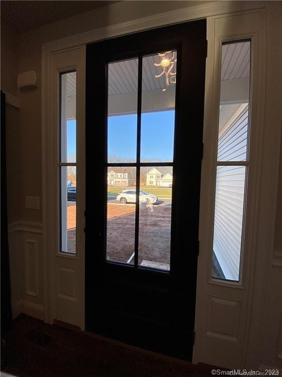 doorway to outside with plenty of natural light and a chandelier