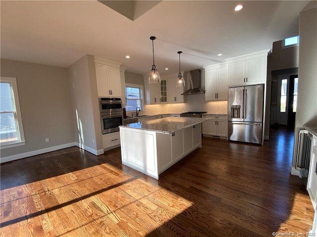 kitchen with hardwood / wood-style flooring, white cabinetry, a kitchen island, stainless steel appliances, and wall chimney exhaust hood