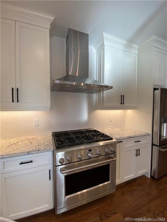 kitchen with dark hardwood / wood-style flooring, tasteful backsplash, white cabinets, stainless steel appliances, and wall chimney exhaust hood