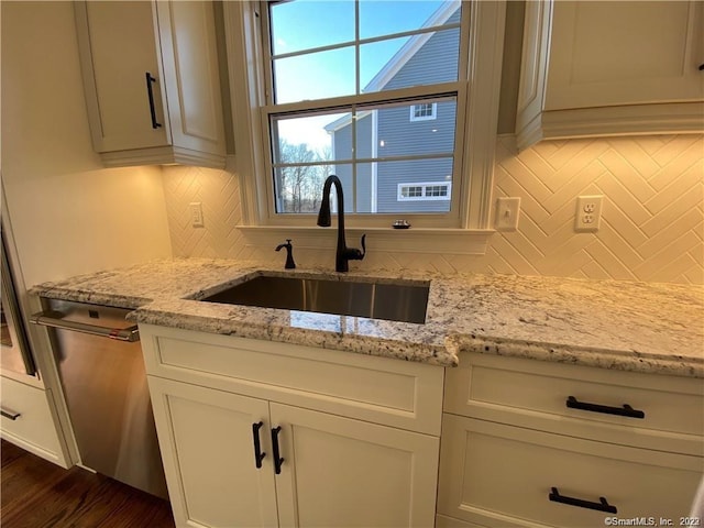 kitchen with tasteful backsplash, light stone counters, dishwasher, and sink