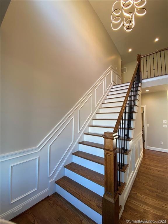 stairway featuring dark hardwood / wood-style floors and a chandelier