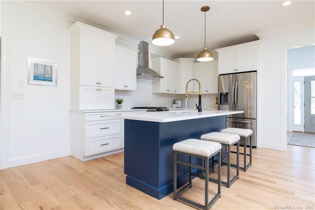 kitchen with a center island with sink, white cabinetry, wall chimney exhaust hood, and stainless steel fridge with ice dispenser