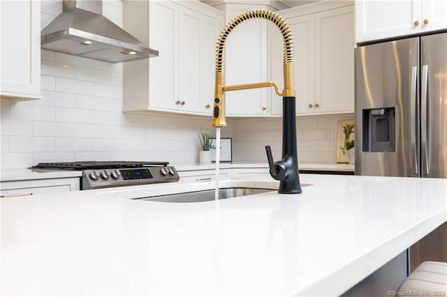 kitchen with backsplash, range, white cabinetry, and wall chimney range hood