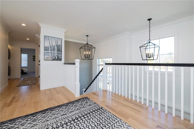 hallway featuring a notable chandelier, light hardwood / wood-style flooring, and ornamental molding