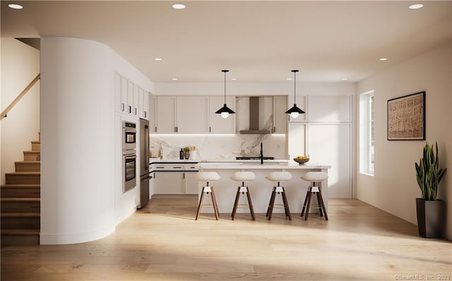 kitchen with white cabinets, wall chimney range hood, hanging light fixtures, and light wood-type flooring