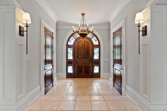 tiled foyer entrance with a notable chandelier and crown molding