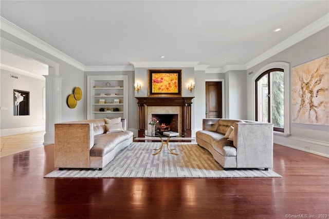 living room featuring crown molding, built in features, and hardwood / wood-style floors