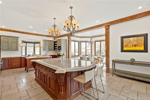 kitchen featuring a kitchen island, a notable chandelier, light tile flooring, a breakfast bar area, and hanging light fixtures