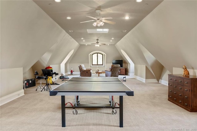 game room with lofted ceiling with skylight, light colored carpet, and ceiling fan