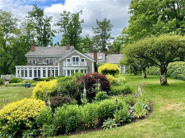 rear view of property featuring a yard and a balcony