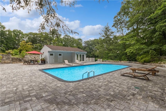 view of swimming pool featuring a patio and an outdoor structure