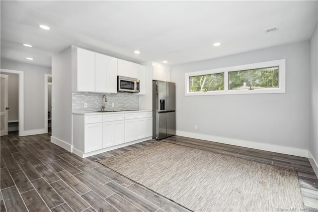 kitchen with tasteful backsplash, appliances with stainless steel finishes, white cabinetry, dark hardwood / wood-style floors, and sink