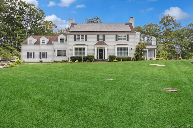 colonial house featuring solar panels and a front lawn