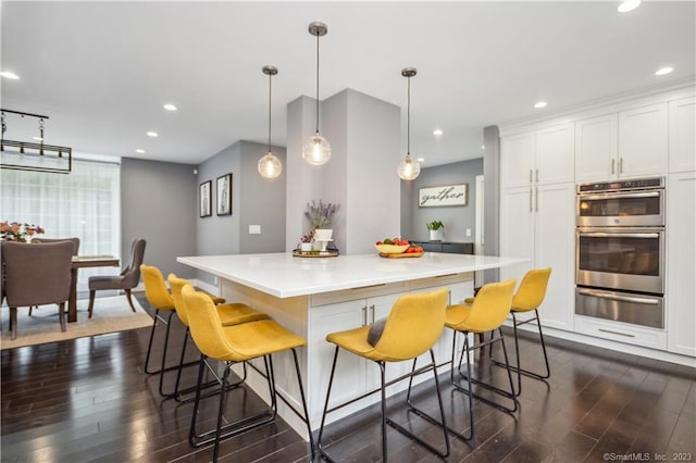 kitchen featuring double oven, a breakfast bar, dark hardwood / wood-style floors, and a center island