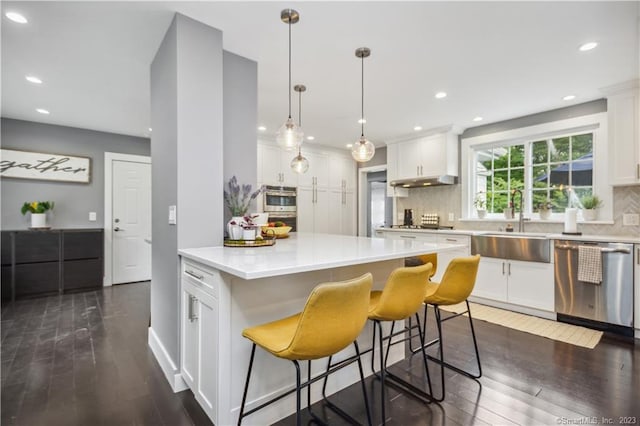 kitchen featuring white cabinets, dark hardwood / wood-style floors, appliances with stainless steel finishes, and tasteful backsplash