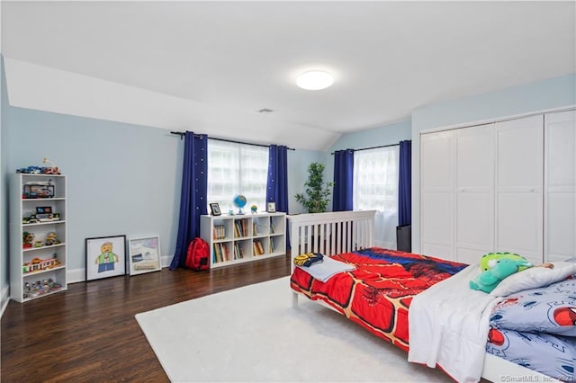 bedroom with lofted ceiling, a closet, and dark hardwood / wood-style flooring