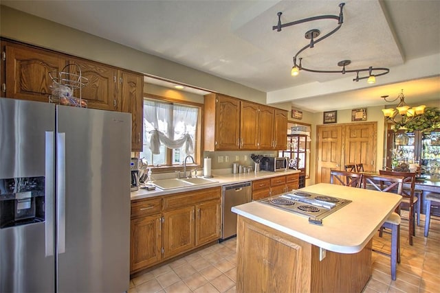 220 W Main St, Mt Zion, IL 62549 - kitchen with stainless steel appliances, light countertops, brown cabinets, a chandelier, and a center island