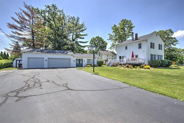 220 W Main St, Mt Zion, IL 62549 - view of front of home with asphalt driveway, a front lawn, a garage, a shed, and a wooden deck