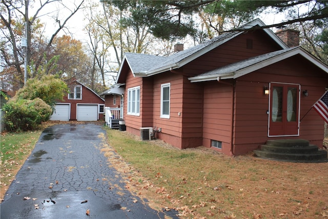 view of side of home with an outbuilding, a yard, a garage, and central air condition unit