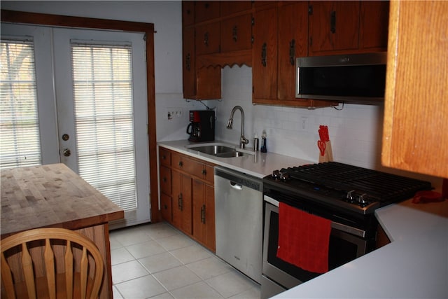 kitchen with backsplash, sink, light tile patterned floors, and stainless steel appliances