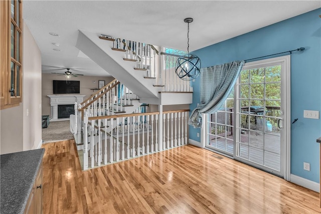 1435 Ashland Ave, Mt Zion, IL 62549 - entryway with wood finished floors, a glass covered fireplace, a ceiling fan, baseboards, and stairway