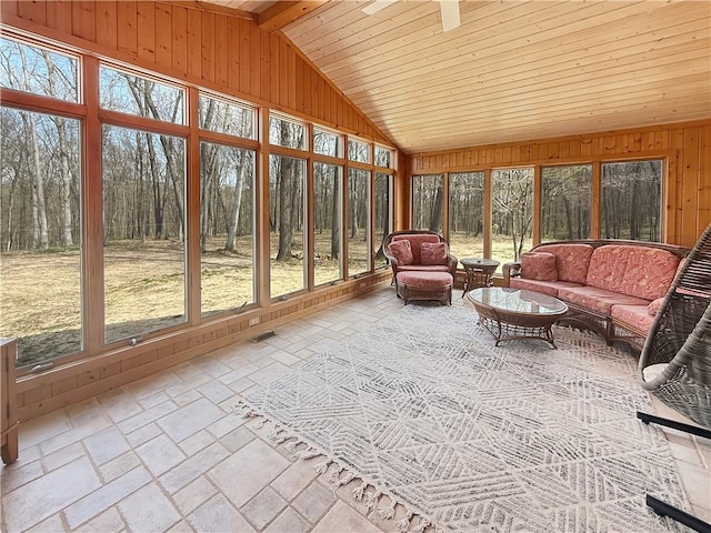 sunroom with lofted ceiling, wooden walls, wood ceiling, and a healthy amount of sunlight