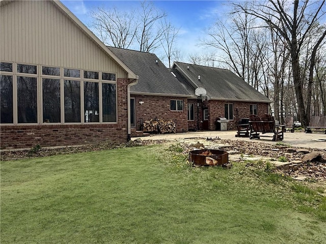 back of house with brick siding, a yard, and a patio area