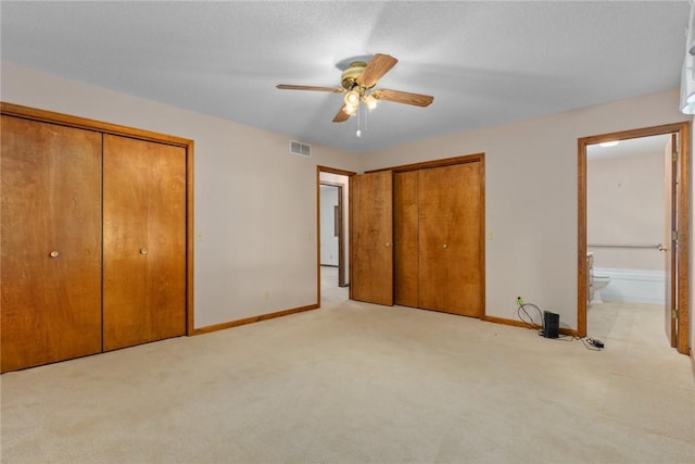 2104 Sycamore St, Effingham, IL 62401 - unfurnished bedroom with two closets, light carpet, connected bathroom, and ceiling fan