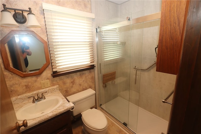 bathroom featuring vanity, toilet, and a shower with shower door