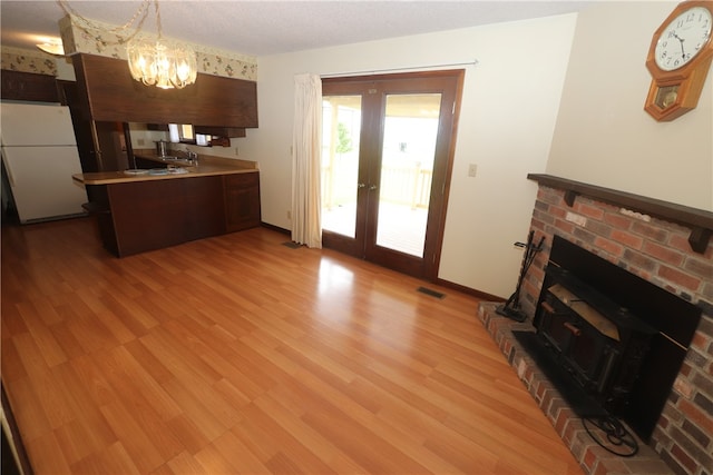 kitchen featuring french doors, light wood-type flooring, white refrigerator, a chandelier, and hanging light fixtures