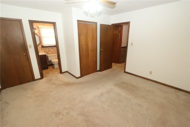 unfurnished bedroom with ensuite bathroom, ceiling fan, and light carpet