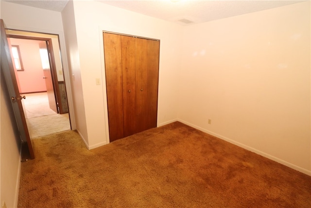 unfurnished bedroom featuring light colored carpet and a closet