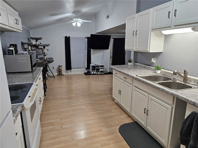 kitchen featuring white electric range oven, light wood-style flooring, a sink, vaulted ceiling, and white cabinetry