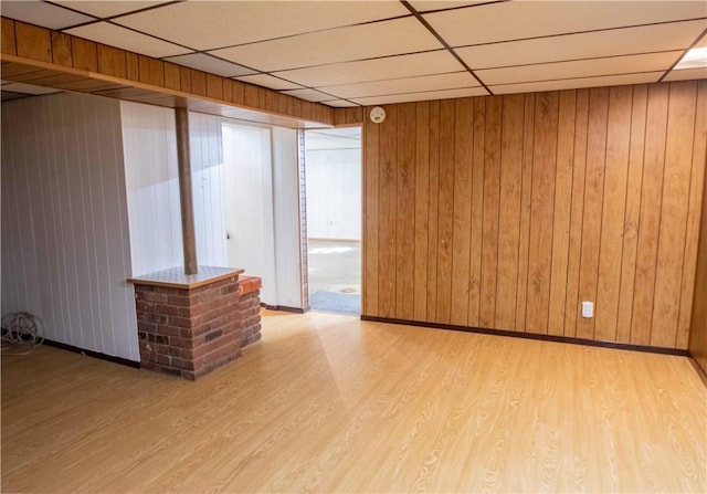 1515 Eastview Ave, Danville, IL 61832 - empty room featuring a drop ceiling, light wood-type flooring, wooden walls, and baseboards