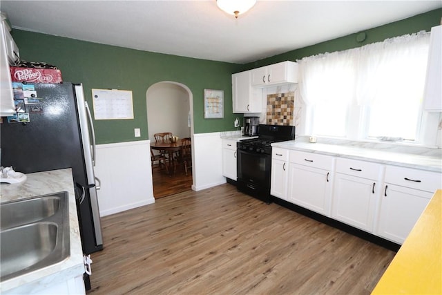 kitchen featuring dark hardwood / wood-style flooring, sink, black gas stove, white cabinetry, and stainless steel refrigerator